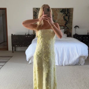 Ljusgul bandeauklänning Moa Mattson x NAKD  - Superfin ljusgul bandeauklänning med broderade blommor. Klänningen är axelbandslös och har en lång, rak siluett som ger en elegant look. Perfekt för sommarens tillfällen när du vill sticka ut med något unikt och romantiskt. Från Moa Mattsons kollektion med NAKD. Prislapp kvar och endast testad 