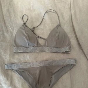 Grå bikini med glittrigt band - Snygg grå bekini, den är använd men syns inte jättetydligt. 