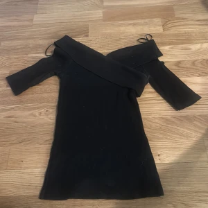 Svart offshoulder klänning från Gina Tricot - Säljer en svart offshoulder klänning från Gina Tricot i storlek XS. Klänningen har korta ärmar och en figurnära passform som framhäver siluetten. Perfekt för dig som gillar stilrena och trendiga plagg.
