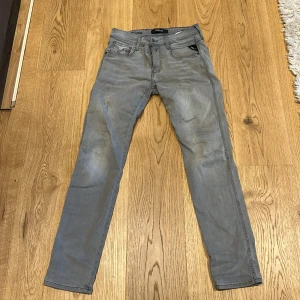Grå Replay Hyperflex jeans - Säljer ett par grå Replay Hyperflex jeans, modell Anbass. Byxorna har fem fickor, dragkedja och raka ben. Perfekta för dig som vill ha ett par snygga och bekväma jeans med stretch.