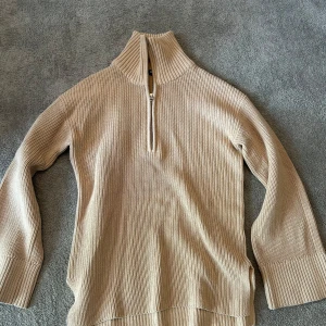 Beige stickad halvzip-tröja  - Säljer en beige stickad tröja från bikbok i storlek XS. Tröjan har hög krage och halv dragkedja framtill, samt långa ärmar och ribbade muddar. 