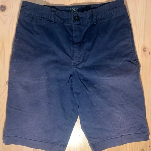 Mörkblå shorts från Polo Ralph Lauren - Mörkblå shorts från Polo Ralph Lauren med klassisk passform. Shortsen har knapp och dragkedja framtill samt fickor både fram och bak. Perfekta för sommardagar och stilrena till vardags.