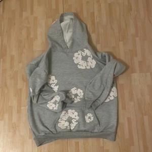 Grå hoodie med vita blommor från Denim Tears - Säljer min feta denim tear hoodie då jag har växt ur den, Funkar nästan för allt. Och har ingen tecken på användning passar dig som är mellan 170-180. Hör av dig för fler frågor