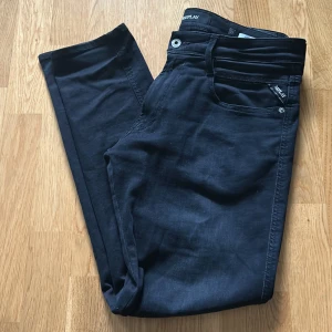 Svarta jeansbyxor från Replay - Säljer ett par svarta jeansbyxor från Replay med klassisk femficksdesign och raka ben. Byxorna har diskreta Replay-detaljer vid fickorna. Perfekta för en stilren look. Storleken är 33 i midjan och 30 i längden. 