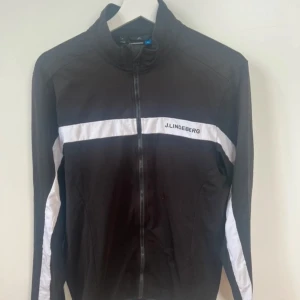 J.Lindeberg Golf Tröja - J.Lindeberg Golftröja – Svart/Vit – Storlek M – Fint skick Sportig och stilren golftröja från J.Lindeberg, perfekt för både bana och fritid. Tröjan är i fint skick, men har en mindre solblekt yta på ryggen, inget som påverkar funktion eller helhetsintryck nämnvärt. Klassisk passform i tekniskt material som andas. 🔹 Färg: Svart med vita detaljer 🔹 Storlek: M 🔹 Skick: Fint (mindre solblekning på ryggen)  ⸻  Liknande märken: Polo Ralph Lauren, Peak Performance, Hugo Boss, GANT, Uniqlo Sport, Adidas