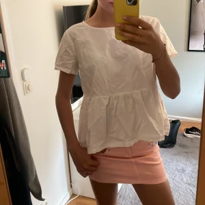 Vit blus med volang - Säljer en söt vit blus med volang nedtill. Blusen har rund halsringning och korta ärmar. Perfekt till sommaren och enkel att matcha med både kjol och jeans. Stl xl men sitter bra på mig me xs/s