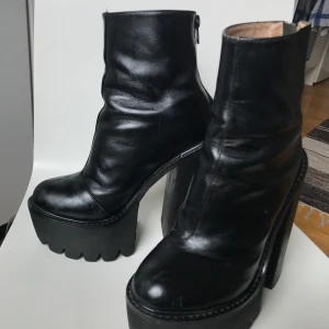 Svarta platåboots med hög klack - Jeffrey Campell platåskor i läder med dragkedja baktill. 15cm höga, men superbekväm modell för dig som är van att gå i klack. Vårdade väl, men finns viss slitage av användning tex creasing. 