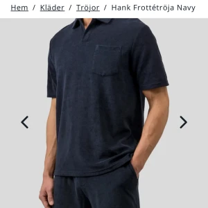 Mörkblå frottépiké - Mörkblå pikétröja i mjuk frotté med klassisk krage och kort ärm. Tröjan har en bröstficka och avslappnad passform, perfekt för en chill och stilren look.