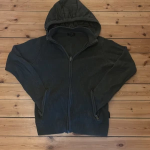 Oliv grön stickad jacka med avtagbar huva från INDICODE - Säljer en mörkgrå stickad jacka från INDICODE i storlek M. Jackan har avtagbar huva, dragkedja framtill och två fickor med dragkedja. Perfekt för lager-på-lager och passar till många olika stilar. Väldigt eftersökt pga den inte säljs längre passar mer L än M.