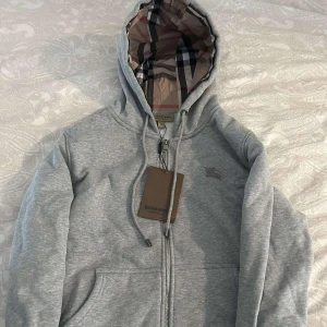 Burberry zip-up Hoodie - En grå zip-up hoodie av märket burberry (aldrig använd)