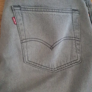 Grå Levis jeansbyxor W31 L32 - Säljer ett par grå Levis jeansbyxor i klassisk rak modell. Byxorna har fem fickor och den ikoniska Levis-loggan på bakfickan. Perfekta för dig som gillar en tidlös och stilren look.