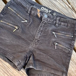 Korta svarta shorts från ONLY! - Korta svarta shorts i stretchig denim och dekorativa dragkedjor fram från ONLY i storlek XL. I mycket fint skick!