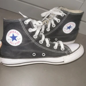Svarta Converse All Star high-top sneakers  - Klassiska svarta Converse All Star high-top sneakers med vit sula och vita snören. Skorna har rund tå, tydliga vita sömmar och Converse-logga på sidan. Perfekta för en avslappnad och cool stil. Nytt pris 700-900