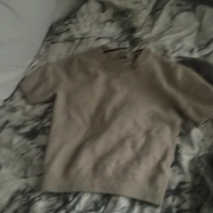 Beige stickad tröja från H&M - Säljer en beige stickad tröja från H&M i storlek XS. Tröjan har korta ärmar och en klassisk, enkel design med ribbad nederkant. Perfekt för lager-på-lager eller som en mysig vardagströja.