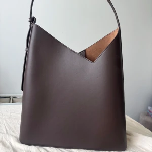 Zara Handväska - Brun / vinröd handväska från Zara. Helt oanvänd och dustbag finns kvar. Det finns en liten kuvertväska/plånbok som man kan koppla på inne i väskan. Skicka för fler bilder eller om du har frågor!