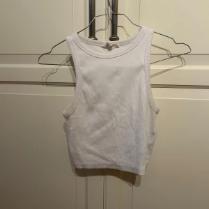 Vit ribbad croppad linnetopp - Säljer en vit croppad linnetopp med ribbad struktur I strl S . Toppen är ärmlös och har en rund halsringning. Perfekt för varma dagar och enkel att matcha med olika outfits.