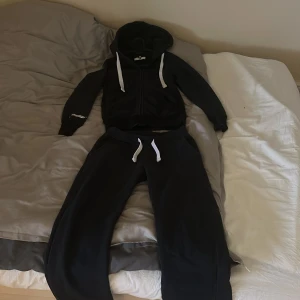 Mörkblå mjukisset från Russemerch - Mörkblå mjukisbyxor och zip tröja från Russemerch, båda plagget är i storlek xs och färgen navy. Byxorna och tröjan har en avslappnad passform och är perfekta för chill dagar. Mjukt material som känns skönt mot huden. Säljer som ett set men går att köpa separat också! Fin kvalitet! 