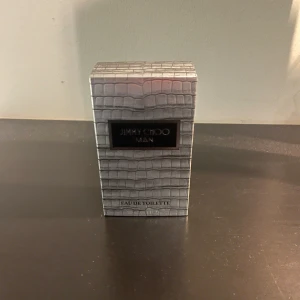 Jimmy Choo Man Eau de Toilette - Jimmy Choo Man Eau de Toilette för herr. Flaskan är stilren i mörkgrått glas med silverfärgad kork och kommer i en lyxig grå ask med krokodilskinnsmönster. Doften är modern och maskulin.