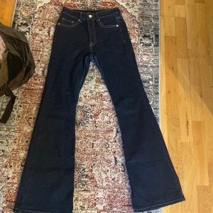 Mörkblå bootcut jeans - Säljer ett par mörkblå jeans med bootcut passform och klassiska fickor både fram och bak. Jeansen har hög midja och är tillverkade i ett stadigt denimtyg. Perfekta för dig som gillar en retroinspirerad look.