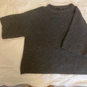 Mörkgrå stickad tröja från 157 - Mysig mörkgrå stickad tröja från 157 med rund halsringning och avslappnad passform. Den är enkel att matcha med olika outfits. Tröjan har ärmar till armvecket ungefär. Lite noppig. Hör av dig vid frågor! 