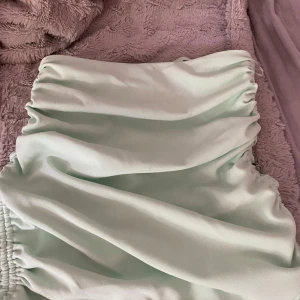 Ljusgrön omlottkjol med rynkade detaljer - Säljer en superfin ljusgrön kjol, man kan ändra hur kort/lång man vill den ska va. Verkligen perfekt till sommaren. skulle säga den passar xs-d☺️