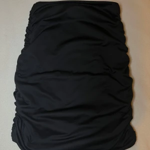 Svart tight kjol med rynkade sidor - Säljer en svart tight kjol med rynkade detaljer längs sidorna. Kjolen har en enkel och stilren design som passar perfekt till många olika outfits. Materialet känns mjukt och följsamt mot kroppen. De är storlek xs men passar s också. Pris kan såklart diskuteras💕