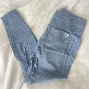 Ljusblå seamless leggings från Gymshark - Säljer ett par ljusblå seamless leggings från Gymshark med hög midja och diskret mönster längs benen. Perfekta för träning och har en bekväm passform. 