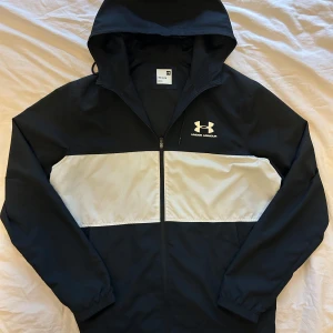 Svart och vit vindjacka från Under Armour - En snygg och trendig jacka från under armour. Bra skick. Storlek L. Jätte nice passform 