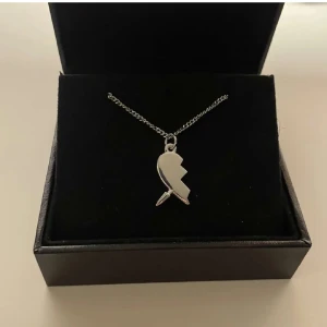 Maria Nilsdotter liknande halsband  - Säljer ett stilrent halsband i silverfärg med ett hänge format som ett trasigt hjärta. Kedjan är tunn och smidig, perfekt för dig som gillar minimalistiska smycken.
