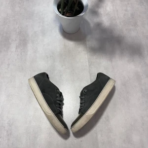 Grå sneakers från Lanvin med gröna detaljer - Säljer ett par grå sneakers från Lanvin med gröna detaljer på tån och vit sula. Skorna har snörning och en klassisk rund tå. Perfekta för dig som gillar stilrena och tidlösa sneakers.