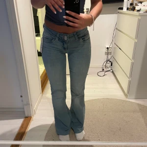 Ljusblå bootcut jeans från nelly - Deras bootcut jeans med rosa där bak, aldrig använda, storlek 34. Sytt upp dom lite för dom var väldigt långa jämfört med de mörkblå jeansen. Men är väldigt bra längd nu skulle jag säga, inte min stil längre därför säljer jag.Är 165cm💕 lågmidjade