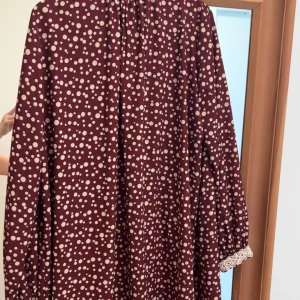 Vinröd prickig klänning med spetsdetaljer.. köpt och gjort  i Korea  - Vinröd klänning med vita prickar. Klänningen har lång ärm och en lös passform med markerad midja. M/S passar både 