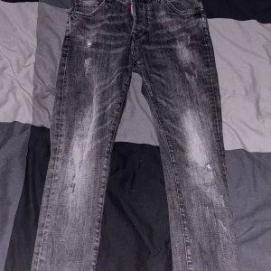 Svarta slim jeans från Dsquared2 - Säljer ett par svarta slim fit jeans från Dsquared2 jeansen har klassisk femficksdesign, dragkedja och knapp i midjan samt Dsquared2-logga på röd etikett vid gylfen.