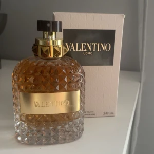 Valentino Uomo Eau de Toilette 100 ml - Exklusiv herrparfym från Valentino i en lyxig, diamantmönstrad glasflaska med guldplatta och svart/guldfärgad spraykork. Doften är elegant och klassisk, perfekt för dig som vill sticka ut. Levereras i originalförpackning. Bara använd någon enstaka gång. 