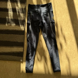 Blå Maya Delorez ridleggings - Säljer mina blåa/guldiga leggings för dom har blivit förstora. Greppet högst upp på insidan av låren börjar försvinna lite grann.