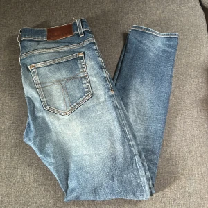 Tiger of sweden jeans - Klassiska blå jeansbyxor med snygga slitningar. Byxorna har normal passform och raka ben. Perfekta till vardags för en avslappnad stil. Jeansmaterialet är slitstarkt och har en autentisk tvättad look.