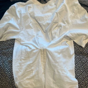 Vit T-shirt med knäppning i magen - Vit T-shirt med knäppning från monki