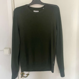 Mörkgrön tröja från Jack & Jones - En stilren mörkgrön tröja från Jack & Jones med rund halsringning. Tröjan har lång ärm och är tillverkad i ett mjukt material som passar perfekt till vardags. Enkel och klassisk design utan synliga detaljer.