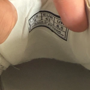 Alexander McQueen vita sneakers med svart häl - Säljer ett par klassiska vita sneakers från Alexander McQueen med svart häl och tjock vit sula. Skorna har rund tå, snörning och är tillverkade i skinn. Perfekta för dig som gillar stilrena och trendiga sneakers.