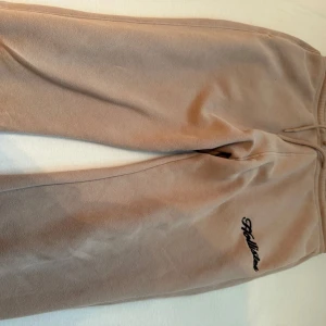 Beige hoodie och mjukisbyxor från Hollister - Säljer en supermjuk och bekväm beige hoodie från Hollister. Perfekt för mysiga dagar eller en avslappnad stil. Den har en klassisk känguruficka och justerbar huva med snören. Hollister-loggan är snyggt broderad på bröstet. Passar perfekt till höst och vinter!