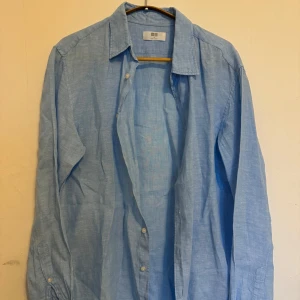 Ljusblå linneskjorta från Uniqlo - Skjortan är sparsamt använd, schysst färg till sommaren