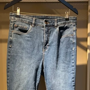 Blå jeansbyxor från Xlnt - kappahl 46 - Säljer ett par klassiska blå jeansbyxor från Xlnt i storlek 46. Byxorna har kurvig passform, hög midja lätt utsvängda ben och fem fickor. Perfekta till dig som gillar en enkel och tidlös jeansstil. 