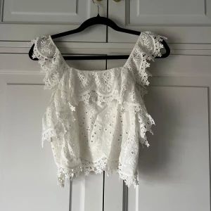 Vit spetsblus från Zara - Säljer en superfin vit blus med spetsdetaljer och volanger från Zara. Helt ny!