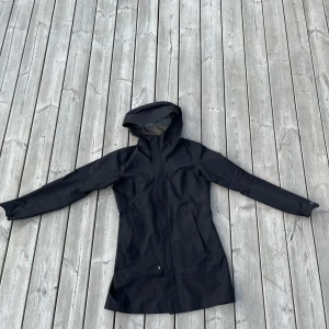 Svart regnjacka med huva från Arc'teryx - Tjena, säljer en fin Arc'teryx jacka i dam modell! Den är använd sparsamt, men har en liten defekt (bild 3) där av priset. Nypris på jackan cirka 4000 tusen kronor. Personen på bilden är cirka 165 cm. 