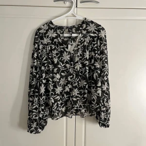 Svartvit blommig skjorta - Vit och svart blommig skjorta. Skjortan är genomskinlig, men perfekt med till exempel en topp.