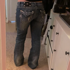 Blå jeansbyxor från Miss Me med broderade detaljer - Säljer ett par blå jeansbyxor från Miss Me med snygga broderade detaljer och dekorativa fickor bak. Byxorna har bootcut-stil och är lågmidjade❤️