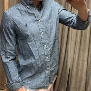 Blå denim skorta från Ralph Lauren - En snygg denim Ralph Lauren skjorta i ett mycket bra skick, killen på bilden är 173 cm lång! Strl XS/S. Priset går alltid att diskuteras
