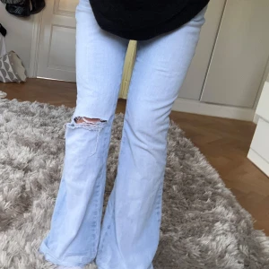 Ljusblå bootcut jeans  - Säljer ett par ljusblå bootcut jeans med slitning och hål på ena knät. Jeansen har låg midja och klassisk femficksdesign. Perfekta för en avslappnad och trendig look. Midjemått 36cm Jag är 165 cm lång och dom är lite långa på mig. Pris går att diskuteras❣️
