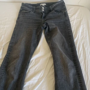 Grå jeansbyxor från Gina Tricot - Säljer ett par grå jeansbyxor från Gina Tricot i klassisk femficksmodell. Byxorna har raka ben, silverfärgade knappar och normal passform. Perfekta för dig som gillar en enkel och stilren look.
