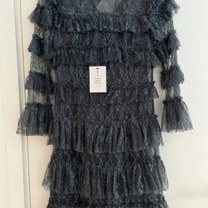 Mörkblå spetsklänning med volanger - Supersnygg mörkblå klänning i spets med flera lager volanger. Klänningen har trekvartsärm och är perfekt för dig som vill sticka ut. Snygg och trendig modell som passar till många tillfällen.